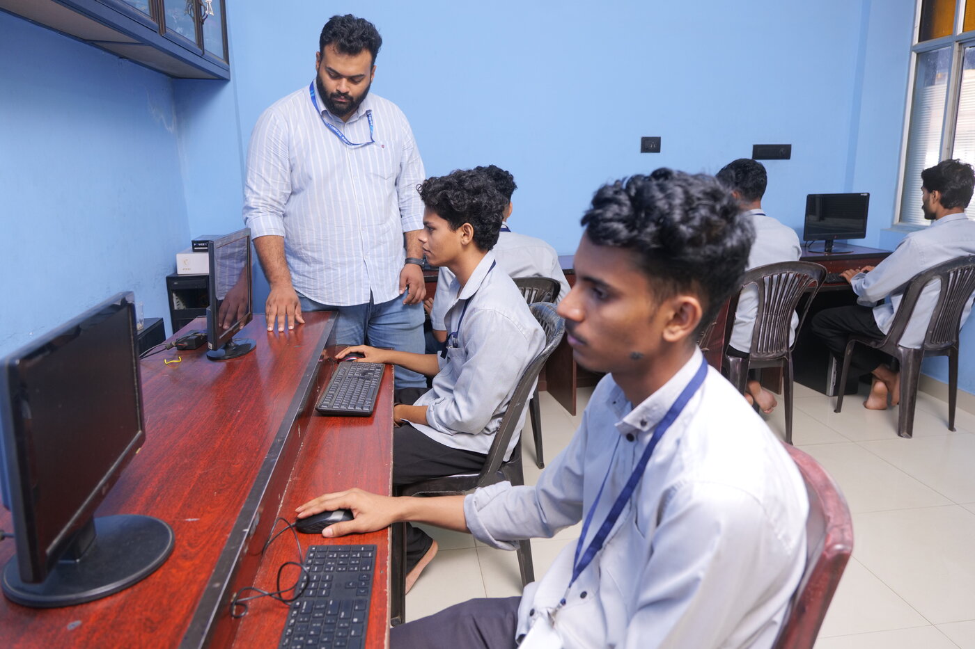 Instructor guiding students at computer terminals