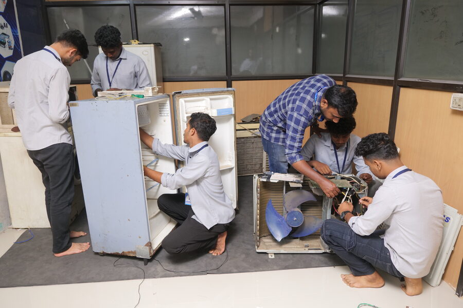 Students disassembling a refrigerator and AC unit in the workshop